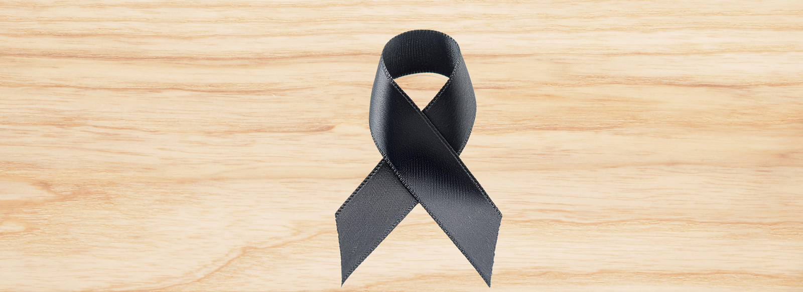 Ruban noir de deuil posé sur une surface en bois clair, symbole de recueillement et de perte