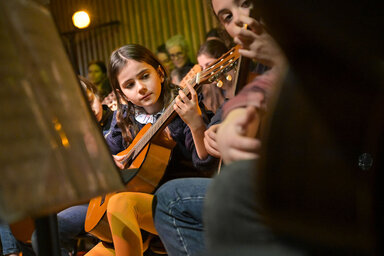 Jeunes élèves jouant de la guitare classique en groupe lors d'un concert, pupitre à partitions au premier plan
